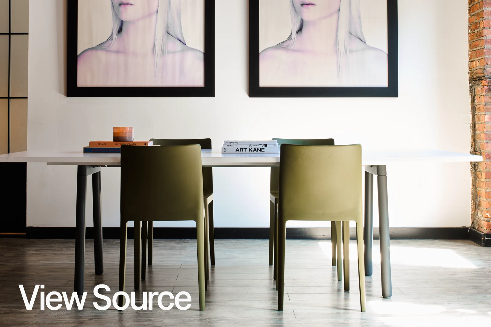 The View Source studio: a long white table under two framed portraits, against exposed brick