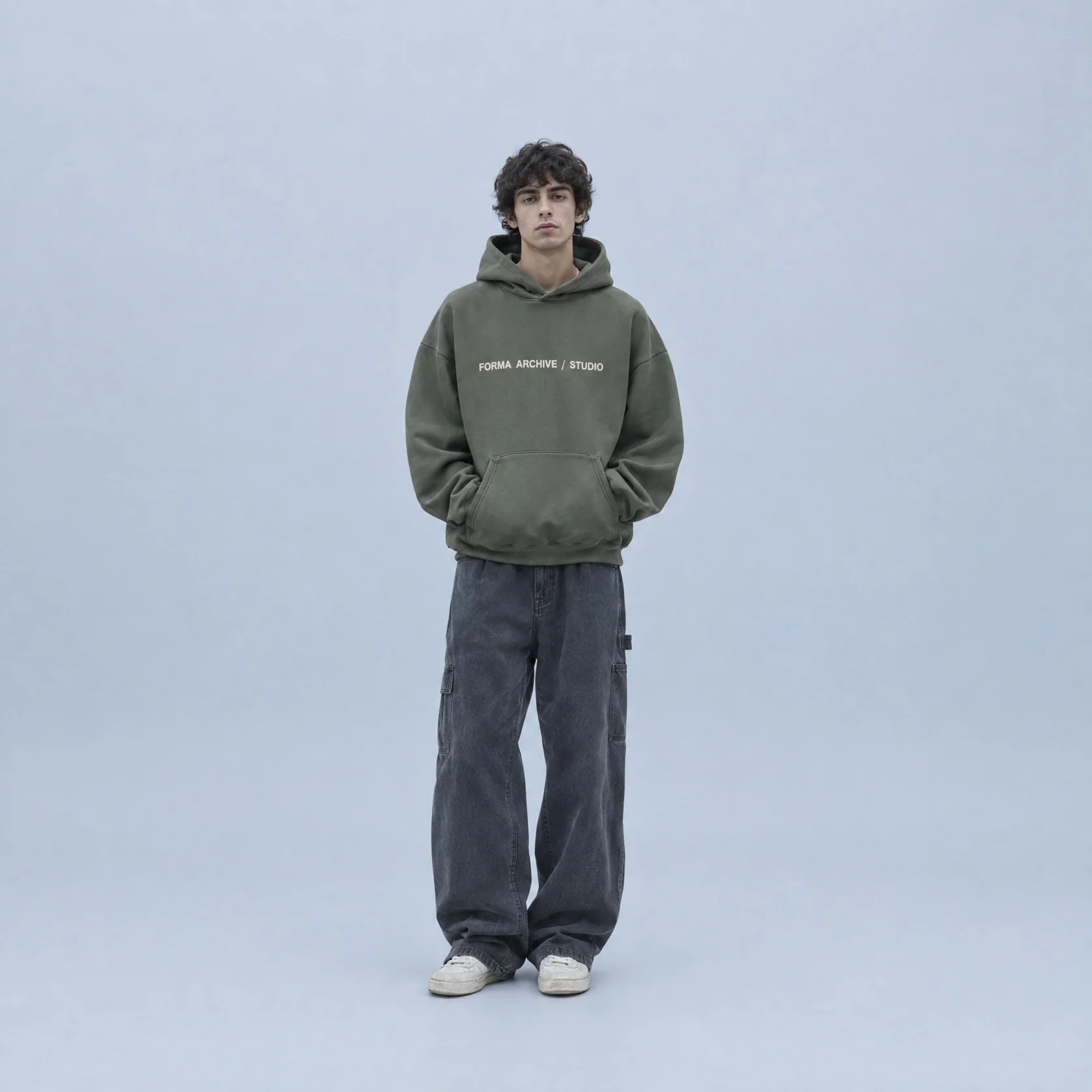 An olive hoodie worn by a model on a studio backdrop
