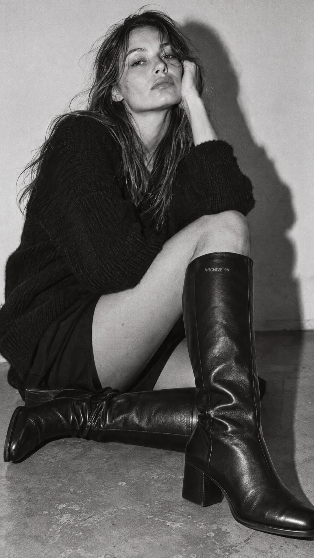 A model in leather boots shot in grainy black and white