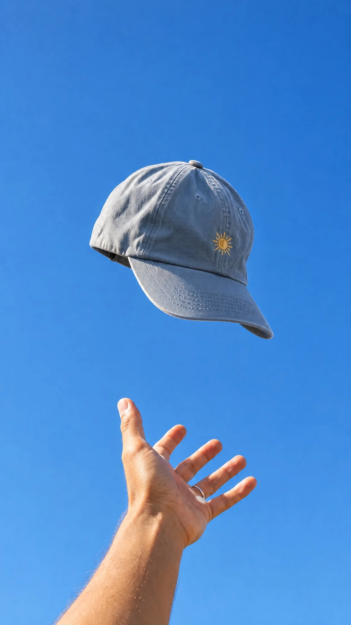 A cap caught mid air above an open hand