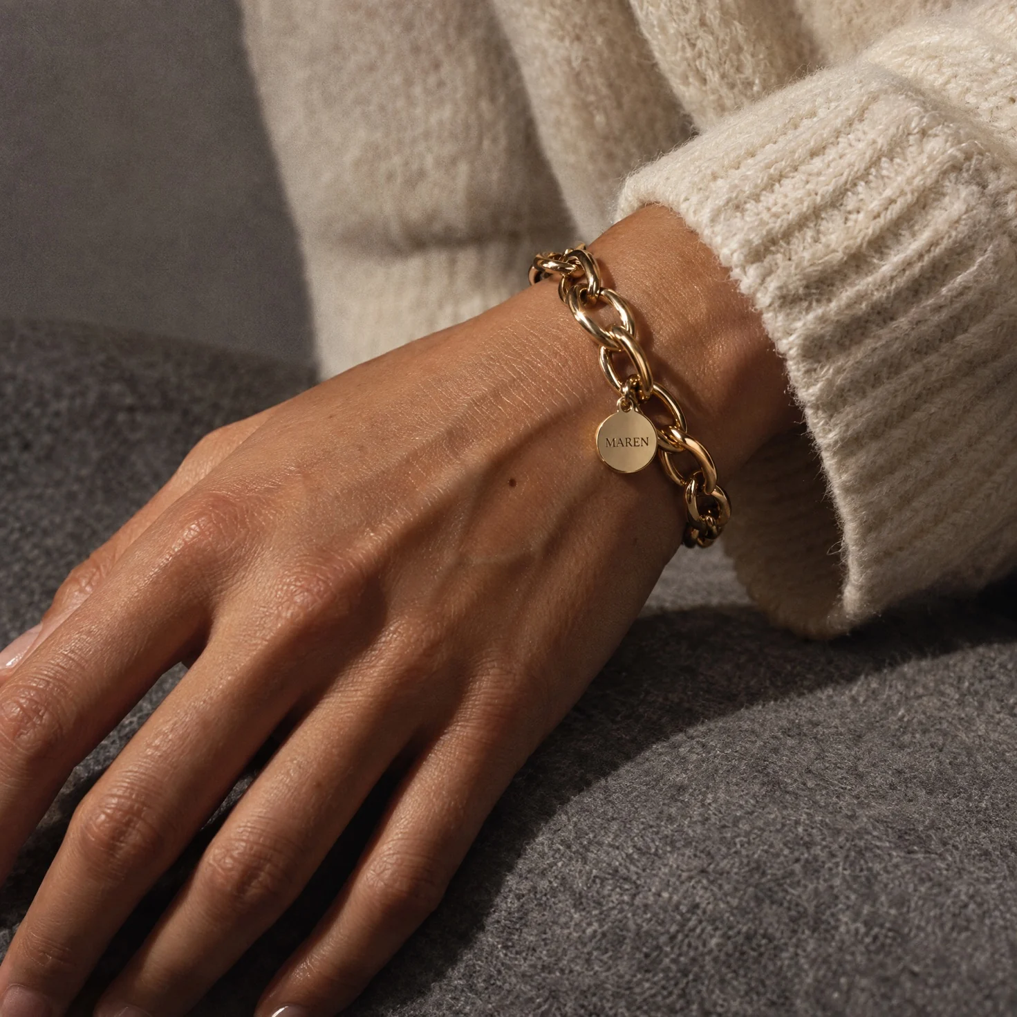 A gold chain bracelet worn on a hand model